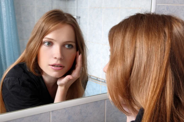 Νεαρή γυναίκα στο λουτρό μπροστά από έναν καθρέφτη επιθεωρούνται δέρμα — Φωτογραφία Αρχείου