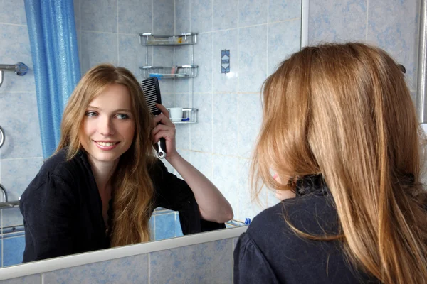 Jovem mulher no banho na frente de um espelho corrigindo cabelos — Fotografia de Stock