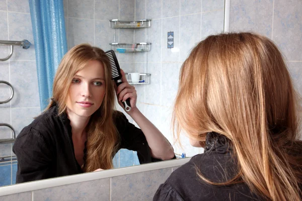 Giovane donna in bagno di fronte a uno specchio correggere i capelli — Foto Stock