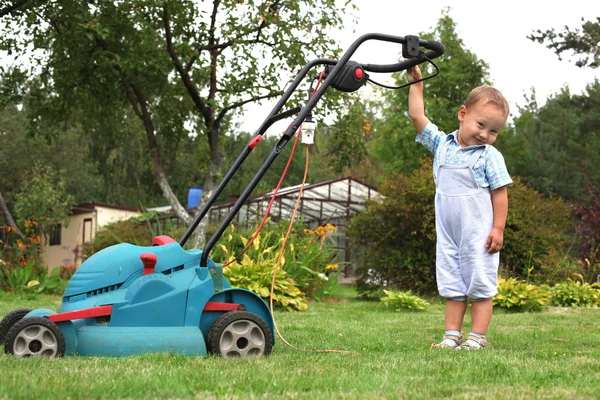 Μικρό αγόρι κηπουρός, κούρεμα του γκαζόν — Φωτογραφία Αρχείου