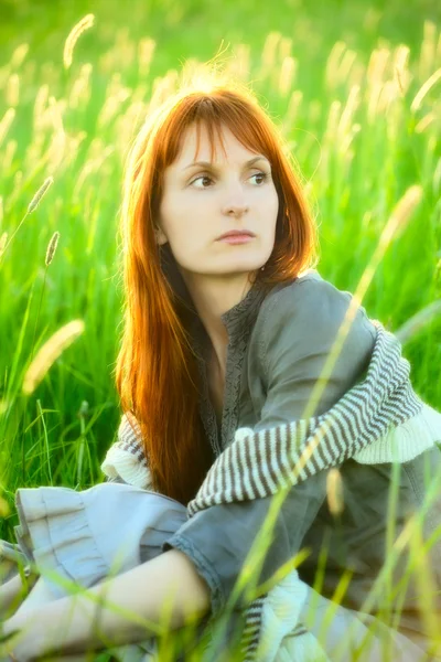 Smutný zrzka žena v trávě — Stock fotografie