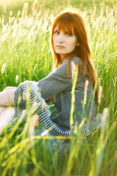 Sad redhead woman in grass — Stok fotoğraf