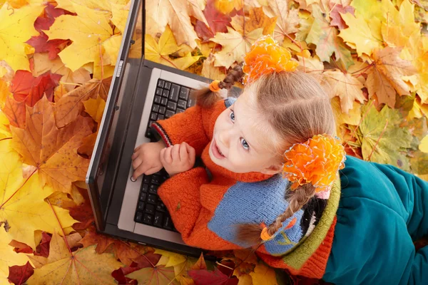 Child in autumn orange leaves with laptop. — Stock Photo, Image