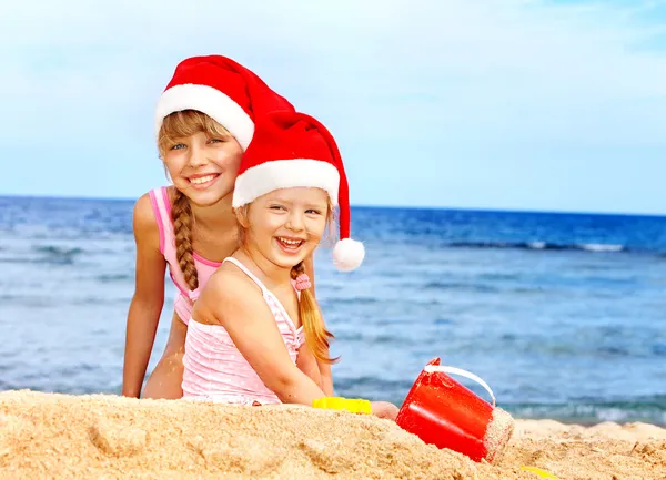 Noel Baba şapkası kumsalda oynarken çocuklarda. — Stok fotoğraf