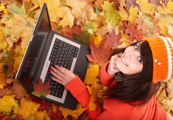 Girl in autumn orange leaves with laptop. — Stock Photo, Image