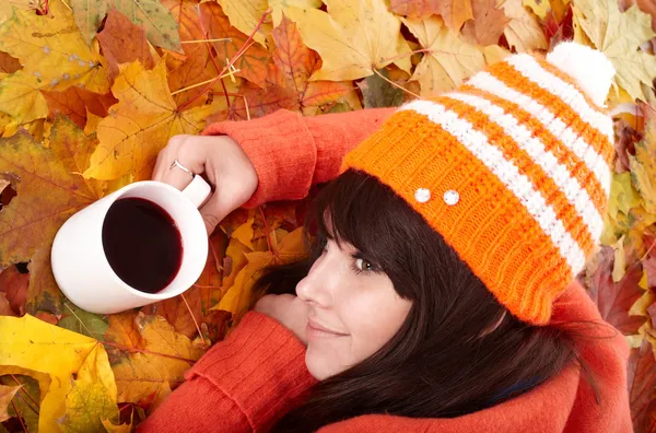 Dziewczyna w orange jesień liście z filiżanki kawy. — Zdjęcie stockowe