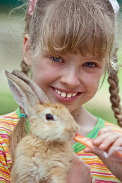 stock image Girl feed rabbit with carrot.