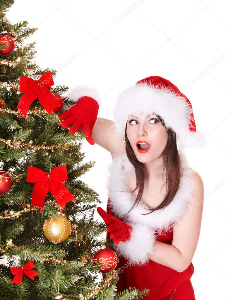 Girl in santa hat near christmas tree.