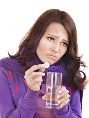 Girl holding glass of water and taking pills. clipart