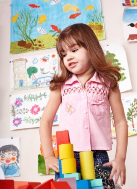 Child with wood block in play room. clipart