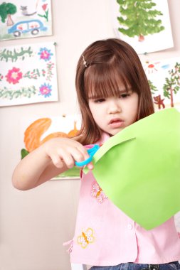 Serious child cutting paper. clipart