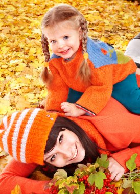 Happy family with child on autumn orange leaves. clipart