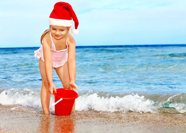 Çocuk kumsalda oynarken santa hat. — Stok fotoğraf