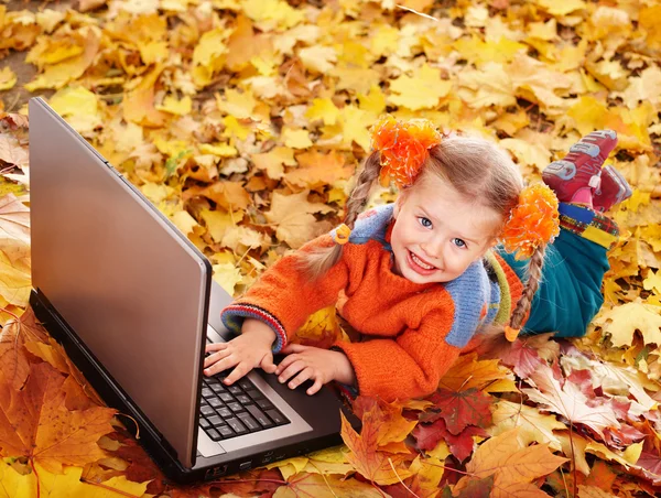 Kind in herfst oranje bladeren met laptop. — Stockfoto