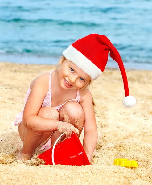 stock image Child in santa hat playing on beach.