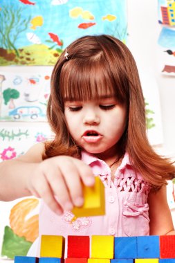 Child with wood block and construction set in play room. clipart