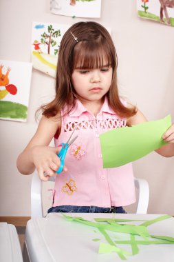 Serious child cutting paper. clipart