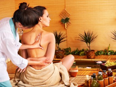 Woman getting massage in bamboo spa. clipart