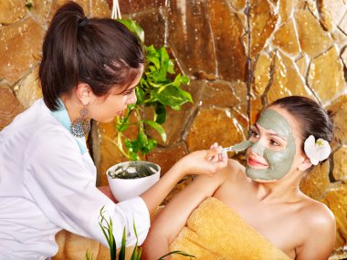 Young woman having clay body mask. clipart