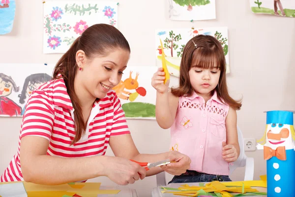 Criança com tesoura cortar papel na sala de jogos . — Fotografia de Stock