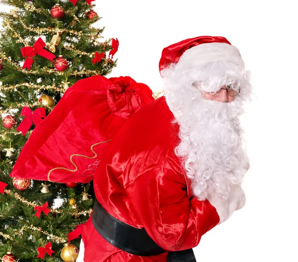 Weihnachtsmann trägt Sack am Weihnachtsbaum. — Stockfoto
