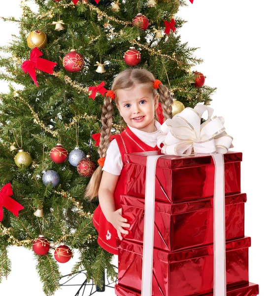 Child giving gift box by christmas tree. — Stock Photo, Image