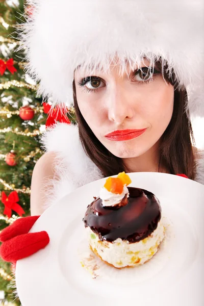 Weihnachtsmädchen mit Weihnachtsmütze und Kuchen essen. — Stockfoto