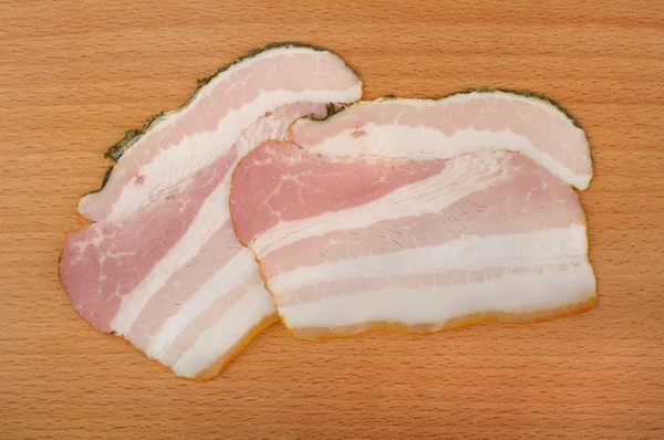 Skivad bacon på en trä skärbräda — Stockfoto