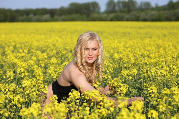 Mulher loira jovem bonita em um campo de flores silvestres . — Fotografia de Stock