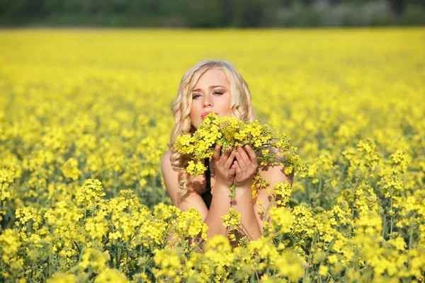 Vackra unga blonda kvinnan i ett fält av blommor. — Stockfoto