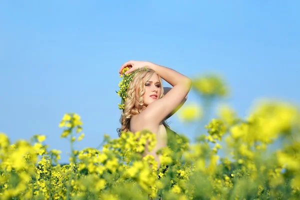 Hermosa joven rubia en un campo de flores silvestres . — Foto de Stock