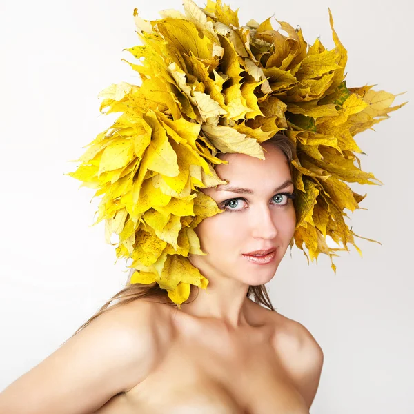 Una niña con una corona de hojas de otoño en la cabeza . — Foto de Stock