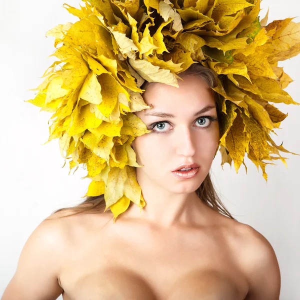 Uma menina com uma coroa de folhas de outono na cabeça . — Fotografia de Stock