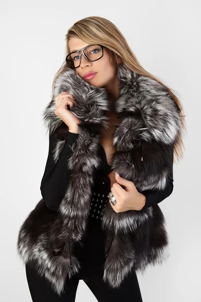 Uma mulher de óculos escuros e um casaco de peles . — Fotografia de Stock
