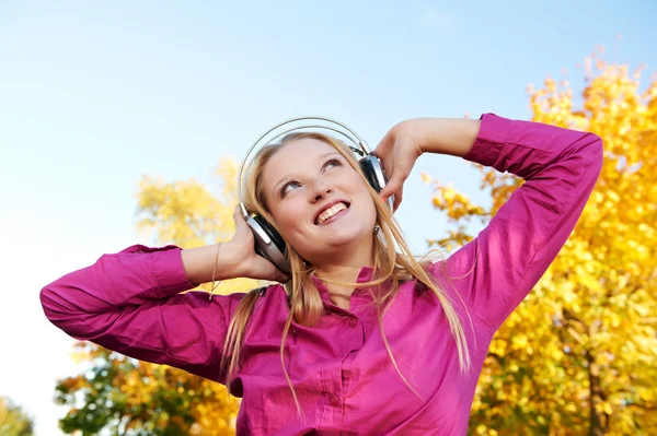 Mulher com fones de ouvido no outono ao ar livre — Fotografia de Stock