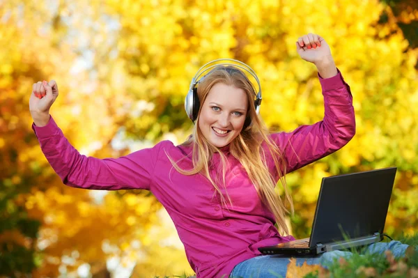 Kulaklıklar ve laptop sonbahar açık havada olan kadın — Stok fotoğraf