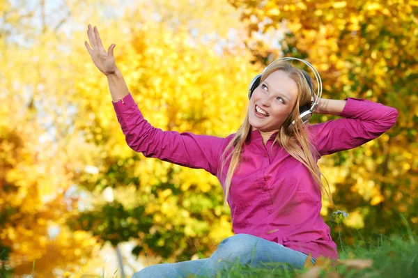 Femme avec écouteurs à l'automne en plein air — Photo