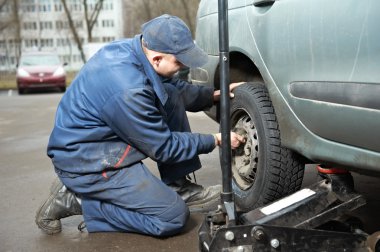 Machanic repairman at tyre fitting with car jack clipart