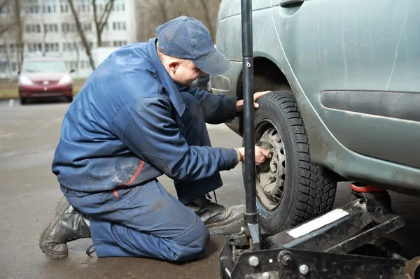 Reparador Machanic no pneu montagem com macaco de carro — Fotografia de Stock