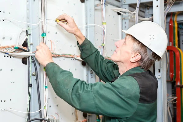 Eletricista maduro trabalhando em chapéu duro com cabos e fios — Fotografia de Stock
