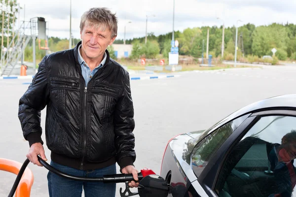 Reifer Mann füllt modernes Auto an Tankstelle mit Benzin — Stockfoto