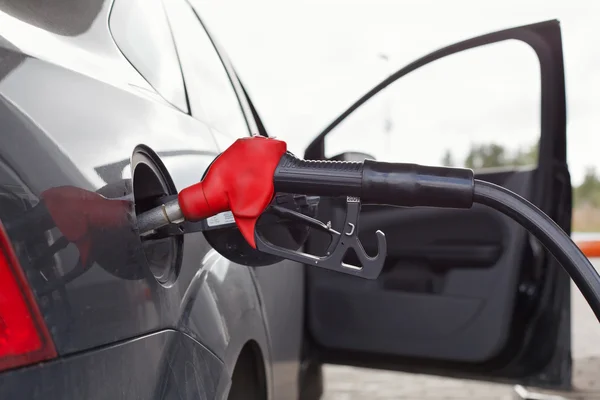 stock image Refueling nozzle in the tank black car at fuel filling column.