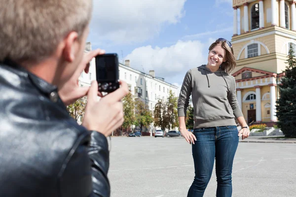 Man photographing young beautiful woman against city`s attractions. — Stock Photo, Image