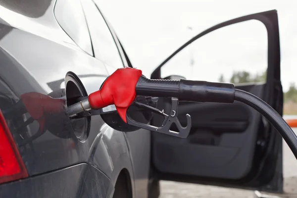 Ugello di rifornimento nel serbatoio auto nera alla colonna di riempimento del carburante — Foto Stock