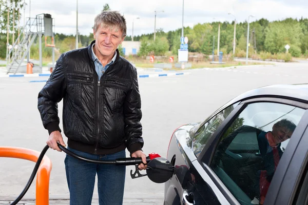 Homem maduro enchendo o carro moderno com gasolina em postos de gasolina — Fotografia de Stock