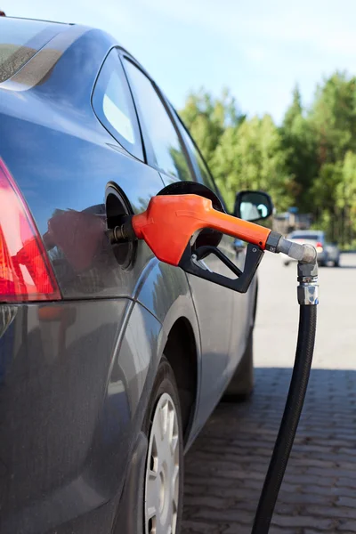 Refueling nozzle in the tank black car at fuel filling column. Summer day. — Stock Photo, Image