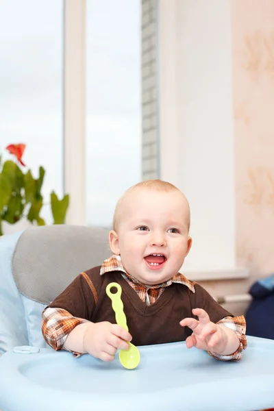 Little kid sitting in highchair and waving his spoon — Stock Photo, Image