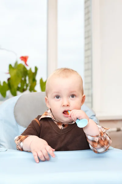 Little kid sitting in highchair and waving his spoon Royalty Free Stock Images