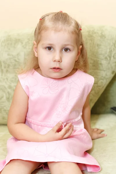 Μικρό παιδί ένα κορίτσι στο ροζ φόρεμα να κάθεται στον καναπέ — Φωτογραφία Αρχείου