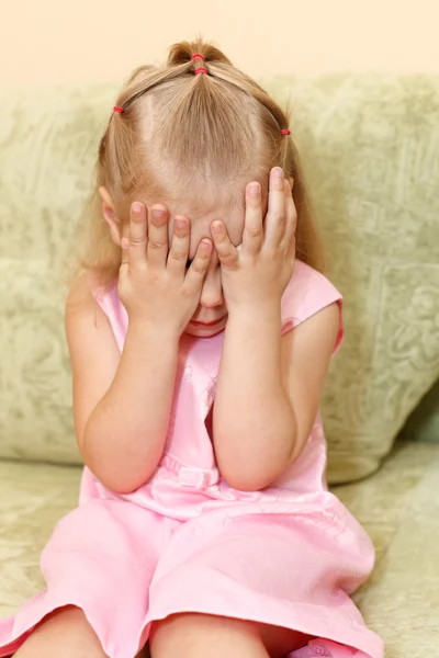 一个女孩在粉红色的裙子坐在国内的房间里的沙发上的小女孩 — 图库照片